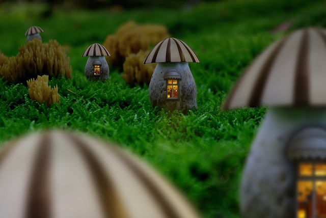 Malé domčeky v tvare húb so zapáleným svetlom v oknách rozložená na tráve.jpg