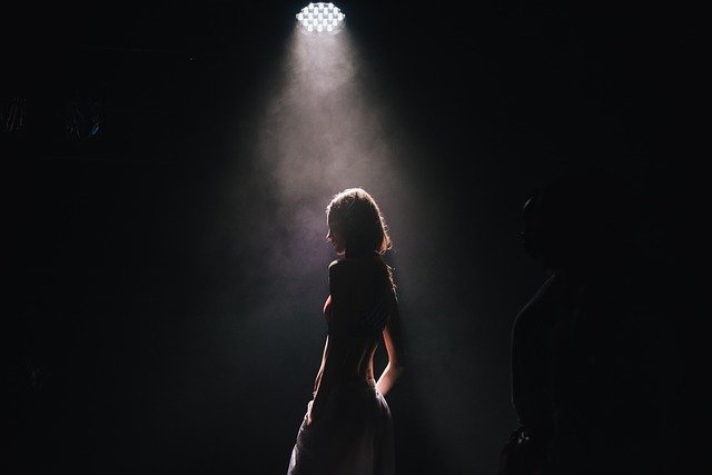 Nahá žena pod reflektorom na pódiu 